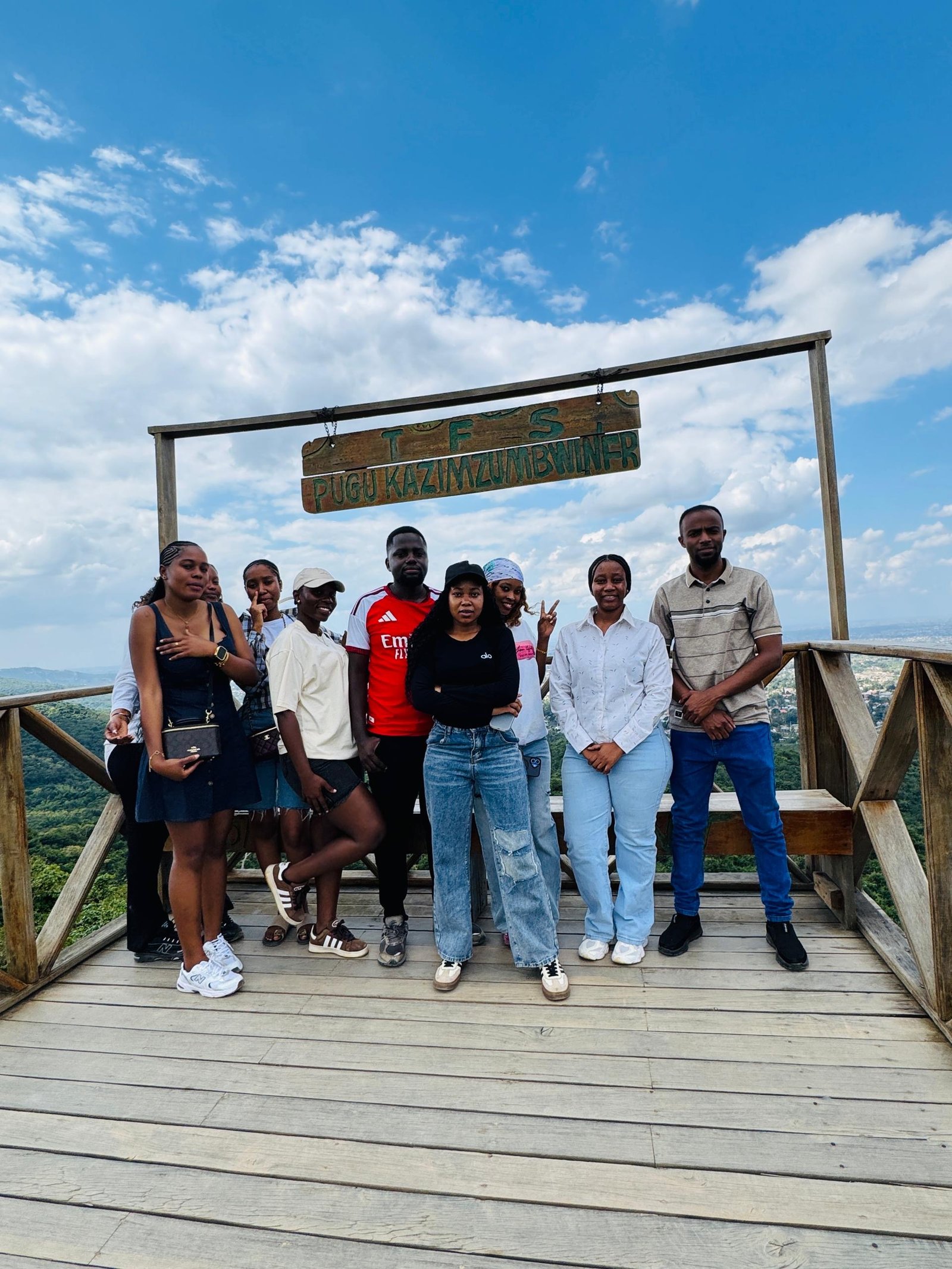 Group of visitors posing at the Dar es Salaam Viewpoint sign overlooking the city